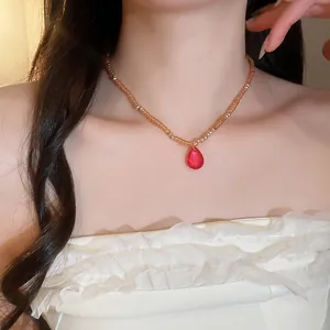 Macro view of a French palace style red teardrop crystal necklace worn by a female model