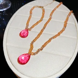 Close-up of French style crystal beaded necklace and bracelet with pink teardrop pendants.