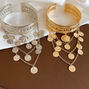 Détail de manchettes dorées et argentées avec chaînes à couches et pendentifs pièces