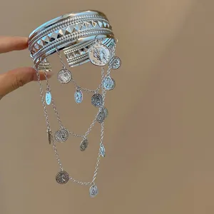 Détail d'un bracelet de bras argenté avec chaînes et breloques de pièces anciennes