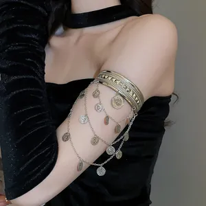 Détail de bracelet de bras argenté avec breloques de pièces sur manche en velours