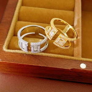 Gros plan de bagues en zircon à double couche en or et argent dans une boîte à bijoux en bois chic.