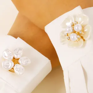 Primer plano de elegantes gemelos de flores con perlas blancas en una camisa blanca