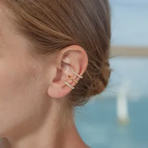 Close-up of three gold-plated stainless steel ear cuffs worn on the ear for women.