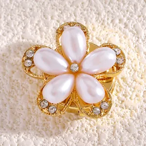 Primer plano de un elegante botón decorativo de flor de perla con filigrana dorada y cristales