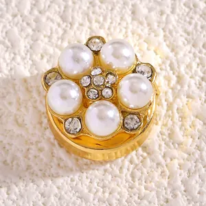Detalle de un elegante broche de flor dorado con perlas blancas y pedrería brillante