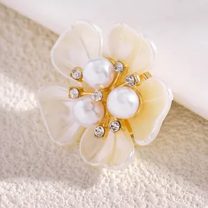 Primer plano de elegantes gemelos de flores decorados con perlas y pedrería dorada