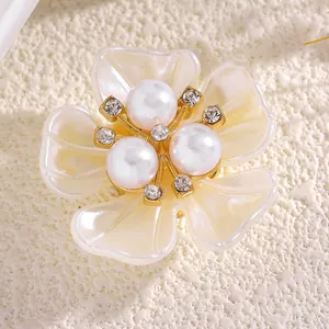 Vista macro de un elegante botón floral de perlas con pedrería y base de tono dorado.