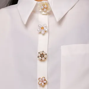 Detalle de elegantes botones de flores con perlas y cristales en una blusa blanca.