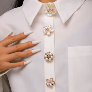 Detalle de elegantes botones decorativos de flores de perlas en camisa blanca.