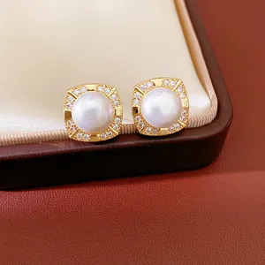 Detailed close-up of elegant gold-plated square stud earrings with zircon and white pearl