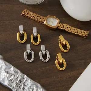 Détail de boucles d'oreilles géométriques en acier titane minimalistes en or et argent.