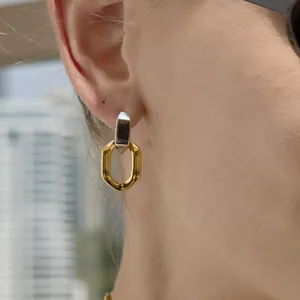 Gros plan d'une boucle d'oreille géométrique bicolore en titane dorée et argentée