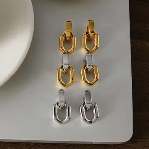 Vue détaillée de boucles d'oreilles à maillons géométriques dorées et argentées.