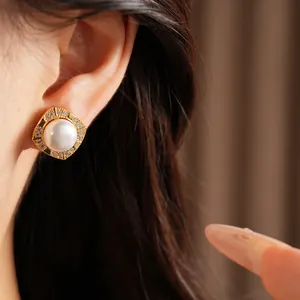Detailed close-up showing a luxurious gold square pearl stud earring worn on an earlobe