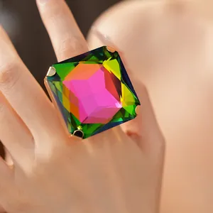 Macro di un grande anello di cristallo arcobaleno quadrato con griffe dorate su un dito