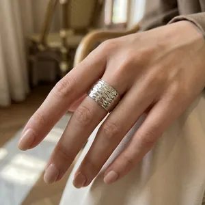 Main portant une bague large en acier titane martelé avec détail de texture minimaliste