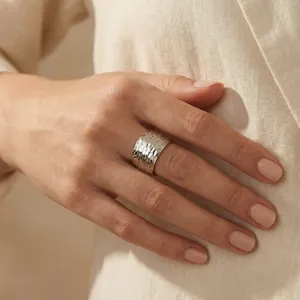 Gros plan d'une bague large minimaliste en acier titane martelé à la main pour hommes et femmes