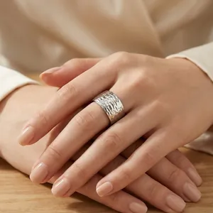 Vue détaillée d'une bague large en acier titane avec texture martelée à la main sur une main.