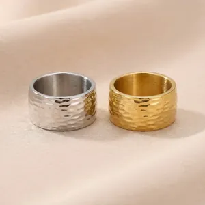 Gros plan de bagues larges en acier titane avec texture martelée or et argent.
