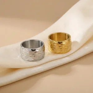 Détail des bagues en acier titane martelé or et argent sur un tissu en soie fine