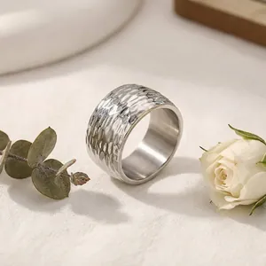 Gros plan sur la texture martelée minimaliste d'une bague large en acier inoxydable.