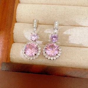Gros plan d'élégantes boucles d'oreilles en zircon rose dans un écrin à bijoux doublé