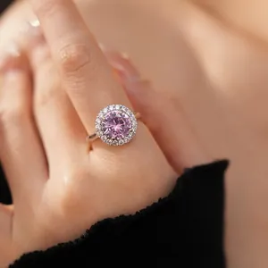 Gros plan d'une bague élégante avec un zircon rose rond entouré d'un halo brillant
