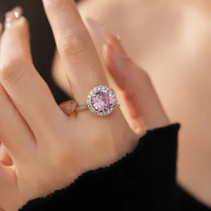 Gros plan d'une bague en argent avec un zircon rose rond au centre et un halo blanc scintillant