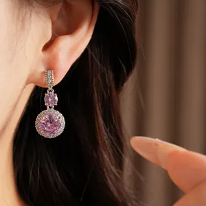 Détail de boucles d'oreilles pendantes avec zircon rose et halo de pierres sur modèle