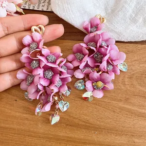Close-up of pink fabric flower tassel earrings with shimmering crystal heart charms