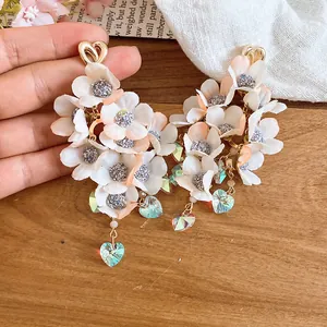 Detailed view of handmade fabric flower earrings with iridescent heart crystals.
