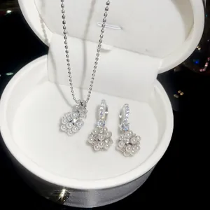 Détail d'une parure de bijoux en argent avec pendentif fleur en perles et boucles d'oreilles