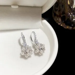 Gros plan sur d'élégantes créoles argentées avec pavé de zircons et fleurs de perles
