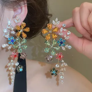 Détail rapproché des boucles d'oreilles fleuries avec cristaux multicolores.