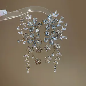 Vue détaillée de boucles d'oreilles fleuries de luxe avec strass bleus et clairs.