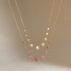 Detailansicht vergoldeter Edelstahlketten mit rosa und weißen Edelsteinen im Nahbild.