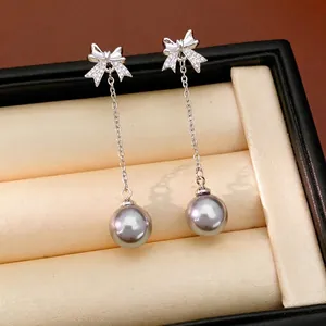 Boucles d'oreilles pendantes nœud élégantes avec perles et détails en zircone.