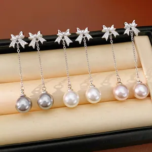 Détail de boucles d'oreilles noeud et perle avec zircones en trois coloris élégants