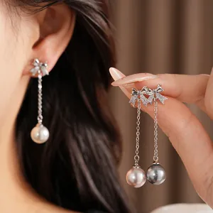 Gros plan d'élégantes boucles d'oreilles nœud et perle avec zircons et perles brillantes