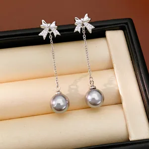 Détail de boucles d'oreilles nœud en argent avec zircons et perles grises.