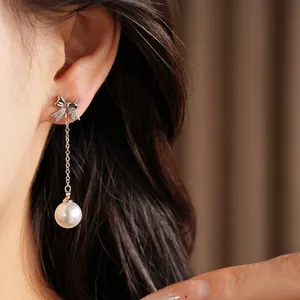 Gros plan d'une élégante boucle d'oreille nœud en zircon et perle sur l'oreille
