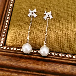 Vue macro du nœud en zircon et de la perle blanche sur d'élégantes boucles d'oreilles