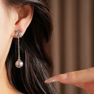 Vue détaillée d'élégantes boucles d'oreilles nœud en argent avec zircon et perle.