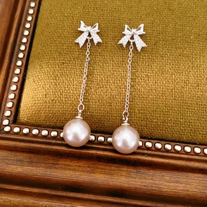 Gros plan détaillé de boucles d'oreilles nœud avec perles pendantes et zircons brillants