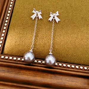 Gros plan de boucles d'oreilles nœud en argent avec zircons et perles grises chic