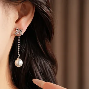 Vue détaillée d'une boucle d'oreille nœud en zircon avec un pendentif en perle