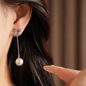 Vue détaillée de boucles d'oreilles nœud en argent avec zircon et perle sur l'oreille