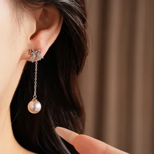 Gros plan détaillé de boucles d'oreilles élégantes en perles et zircon portées sur l'oreille.