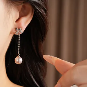Détail de boucles d'oreilles élégantes en forme de nœud avec zircon et perles pendantes